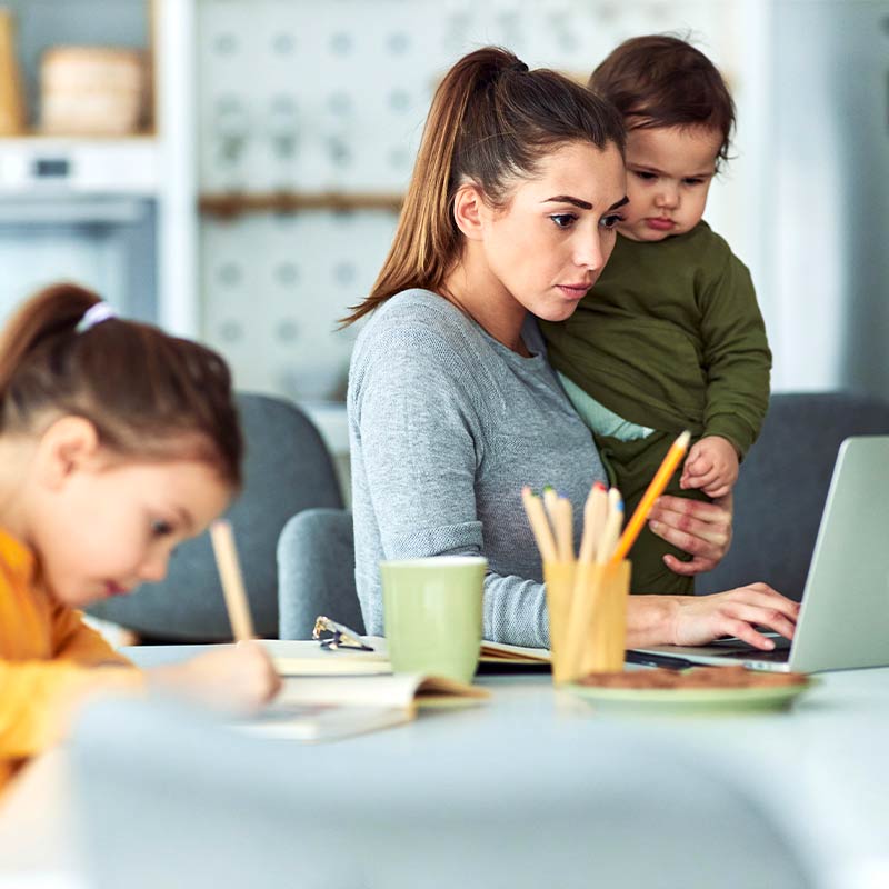 Mom with kids sitting at a laptop ready to plan homeschool week.